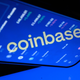 An illustration with the Coinbase logo reflected on a phone screen.